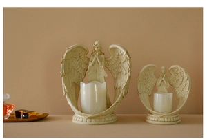 Detail of angel candle holders in white resin with wings and a praying pose