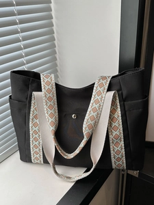 Borsa tote nera minimalista con ampia tracolla etnica geometrica su un davanzale