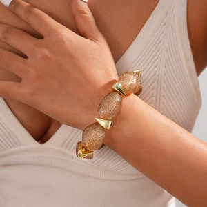 Close-up of sparkling gold-brown resin beads with metal claws on elastic bracelet