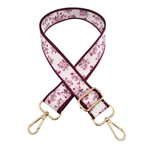 Detail of adjustable floral replacement bag strap with golden hardware on white background