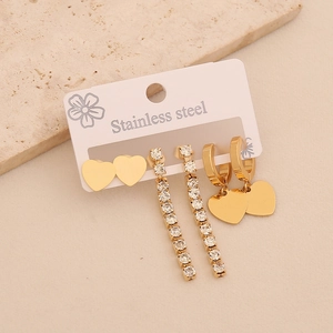 Detailed view of three pairs of gold stainless steel heart and rhinestone earrings on a card
