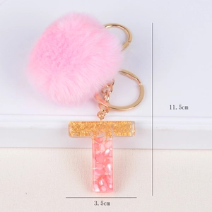 Detail shot of a pink pompom keychain with a 11.5cm resin letter T charm and gold ring
