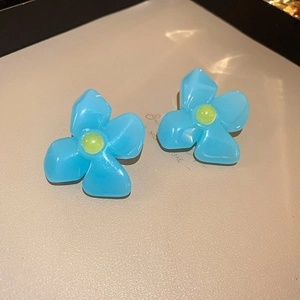 Détail de boucles d'oreilles fleurs en résine bleu ciel avec centres jaunes sur plateau