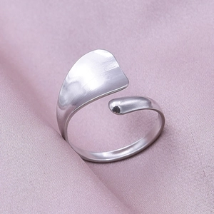 Detailed close-up of adjustable silver steel ring with geometric matte finish on silk