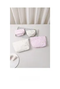 Detail view of pink and white striped makeup bags with heart embroidery and zippers