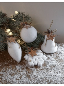 Close-up of white flocked Christmas ornaments with natural pine cones and twine loops