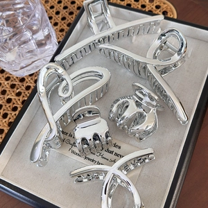 Macro detail of glossy silver metal hair claws set in a luxury display tray