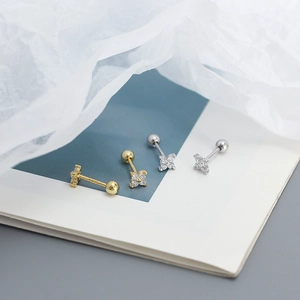Detailed macro view of clover stud earrings with sparkling zircons in gold and silver