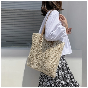 Detail of hand-woven beige tote with textured crochet pattern and brown leather straps