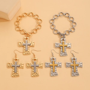 Detailed close-up of textured cross earrings and bracelet with hammered metal finish
