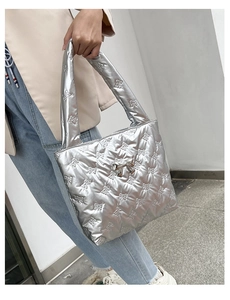 Close-up of silver quilted tote bag featuring metallic bow texture and hanging charm