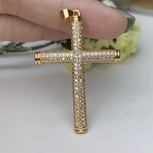 18k gold plated cross pendant featuring sparkling cubic zirconia held by fingers