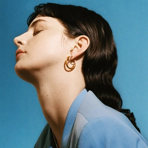 Double layered gold and silver stainless steel earrings worn by model on blue background