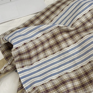 Close-up of fabric tote bag featuring vintage plaid, stripes, and fringe detail