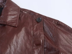 Detail of red-brown leather jacket shoulder with epaulette and black button