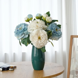 Artistic oil-painted style faux peony bouquet in a dark green ceramic vase on a wooden table