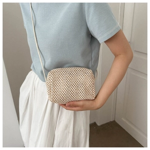 Detail of handmade woven straw crossbody bag showing texture and summer mini square style