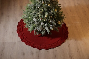 Close-up of red cable knit Christmas tree skirt with textured pattern and wavy edges