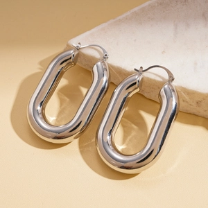 Close-up of polished silver U-shaped hoop earrings resting on a textured stone base