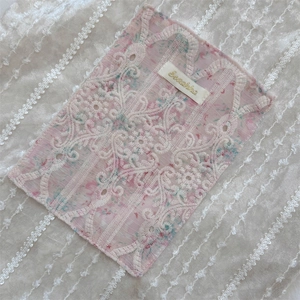 Vue détaillée de la broderie en dentelle blanche et du tissu floral rose du sac à main