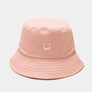 Détail d'un chapeau bob en toile rose avec broderie smiley blanc et texture en coton