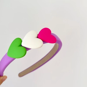 Detail of purple sponge headband featuring colorful green, white and pink heart ornaments