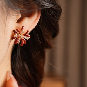 Close-up of 18k gold plated red flower earrings with zircon on a model's ear