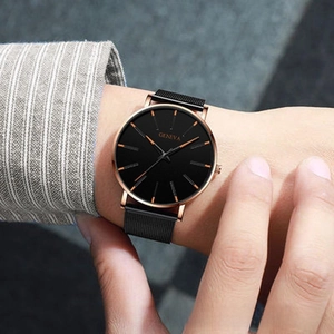 Close-up of minimalist rose gold watch with black dial and mesh steel strap on wrist