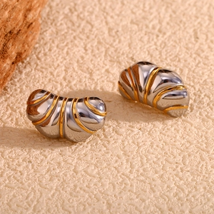 Gros plan de boucles d'oreilles croissant bicolores or et argent sur texture pierre