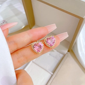 Pink heart crystal earrings with gold trim and halo diamonds displayed in a box