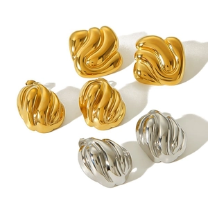 Geometric twisted metal hoop earrings in gold and silver finish on white background