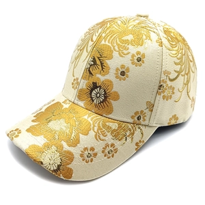 Detailed close-up of golden floral embroidery on off-white vintage style baseball cap