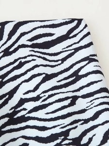 Detailopname van zebraprint stof met fijne kepertextuur op een blazer en rokset
