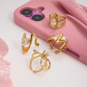 Close-up of four gold stainless steel rings set with zircon on a pink background
