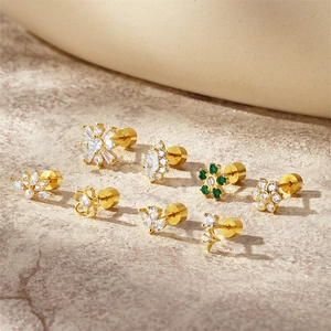 Close-up of gold-plated silver earrings with white zircon and green crystals