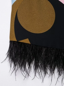 Detalle de la blusa con estampado geométrico y ribete de plumas negras en el puño