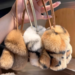 Detailed view of three real rabbit fur bunny charms in brown and spotted white colors