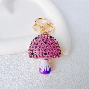 Macro view of mushroom keychain with pink rhinestones and purple resin on golden ring