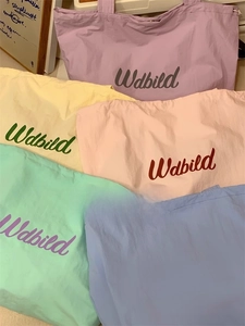 Macro shot showing five pastel colors of the drawstring tote bag with printed logo