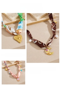 Détail de colliers en foulard de soie coloré avec pendentifs soleil et lune dorés