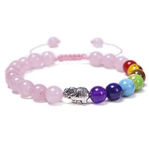 Detail of hand-woven bracelet with natural rose quartz, chakra beads and silver elephant charm