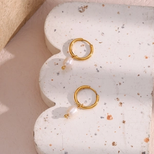 Macro detail of 18K gold-plated hoop earrings with natural freshwater pearl pendants