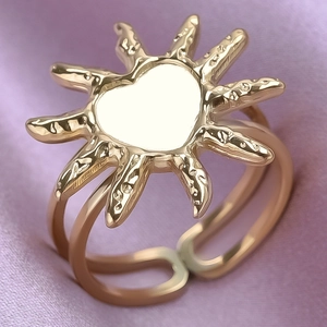 Close-up of golden sunburst heart ring with adjustable double-layer band on silk