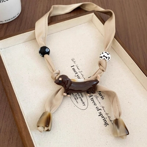 Dachshund ribbon necklace with paw and bone beads on minimalist display tray