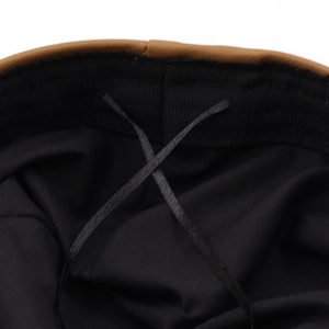 Interior detail of black PU leather beret showing brown trim and adjustable straps