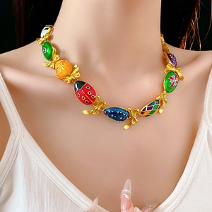 Dettaglio collana vintage dorata con pendenti in smalto colorato e fiocchi d'oro