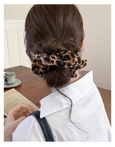 Macro view of a leopard print scrunchie worn on a ponytail in a cozy setting