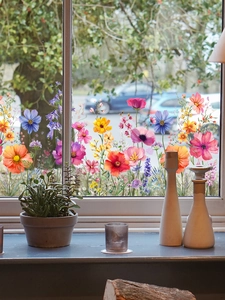 Colorful floral static window clings displayed on a glass pane with home decor items