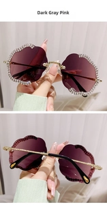 Detailansicht der blumenförmigen dunkelgrau-rosa Sonnenbrille mit glitzernden Strasssteinen