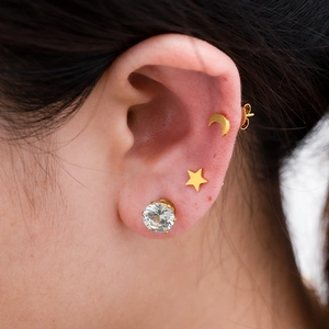 Close-up of minimalist 18K gold plated stud earrings with star moon and zircon on ear